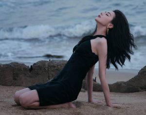 迪丽热巴光着美足踩在海滩上，身着黑裙展露迷人风姿（第2张/共14张）